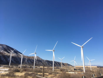 Windmill on field against clear blue sky