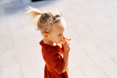 High angle view of girl eating food while standing outdoors