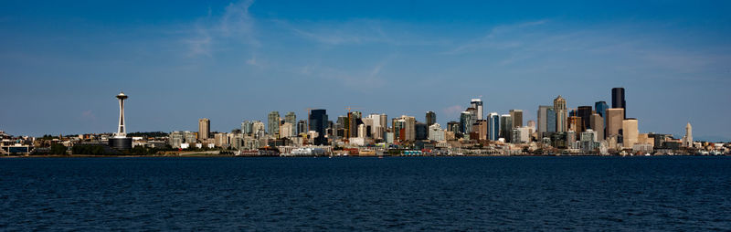 Sea by modern buildings in city against sky