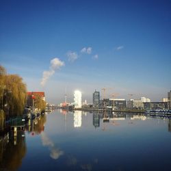 Reflection of factory on water against sky