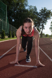 Portrait of young woman bending at track field