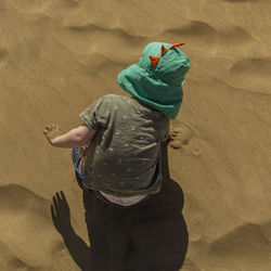 High angle view of boy playing with sand at beach