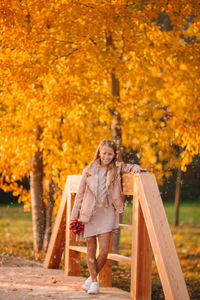 Portrait of smiling girl standing against autumn tree