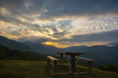 Empty chairs and table against mountains at sunset