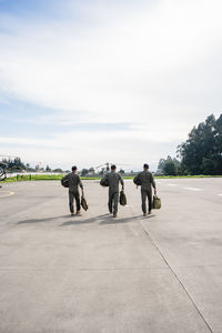 Rear view of military men walking on runway against sky