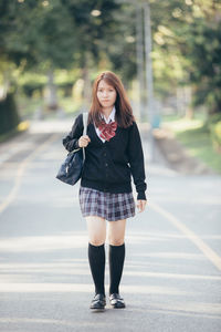 Portrait of young woman walking on road