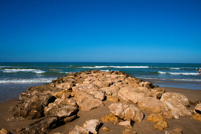 Rocks on beach against clear blue sky