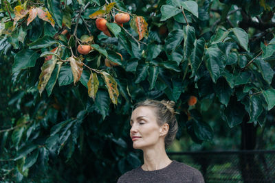 Portrait of young woman standing against plants