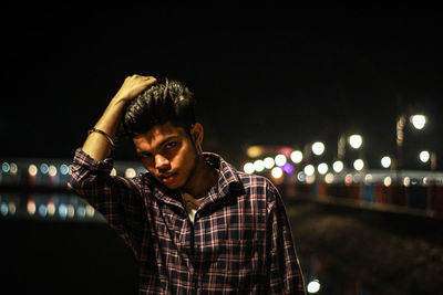 Young man looking at illuminated city at night