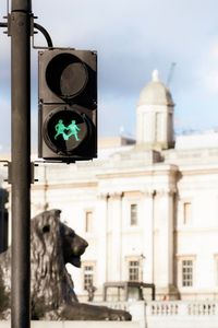 Road signal against building and sky