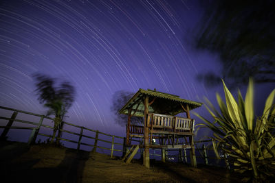 Low angle view of gazebo on field against star trails