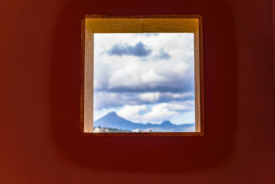 Low angle view of cloudy sky seen through window