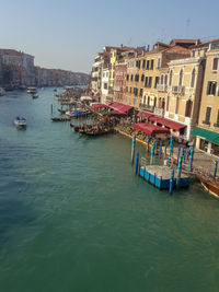 Boats in canal amidst city against clear sky