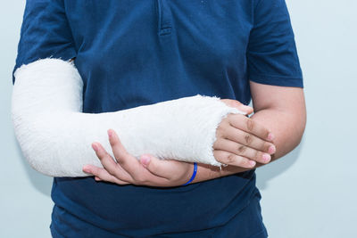 Midsection of person with injured hand against wall