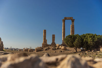 Rear view of man standing on rock against clear sky