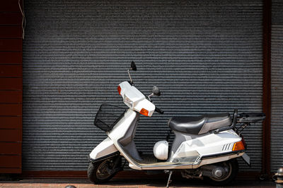 Motor scooter parked on street against brick wall