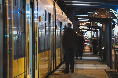 People standing by train at railroad station platform