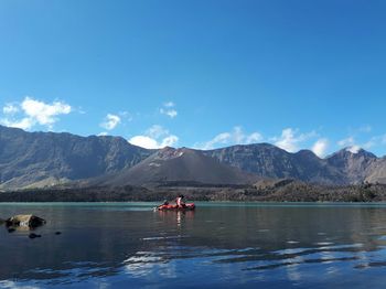 Scenic view of lake and mountains against blue sky