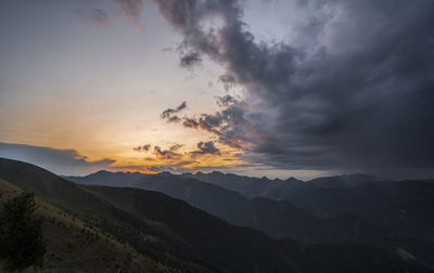 Scenic view of mountains against dramatic sky during sunset