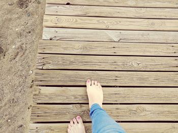 Low section of woman walking on boardwalk