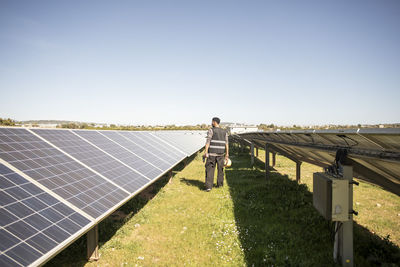 Rear view full length of male engineer examining solar panels at power station