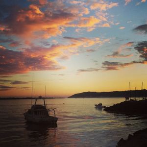 Boats in sea at sunset