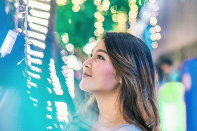 Close-up of young woman amidst illuminated lights