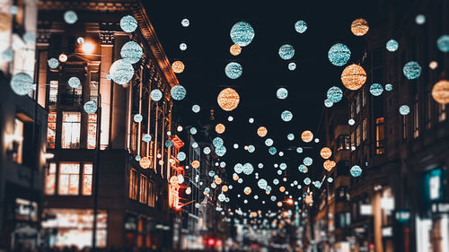 Low angle view of illuminated lanterns hanging amidst buildings in city at night