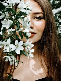 Close-up portrait of woman with flowers outdoors