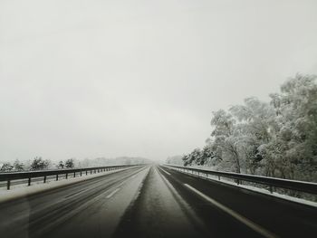 Road amidst trees against sky during winter