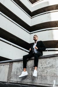 Full length portrait of a young man sitting on staircase