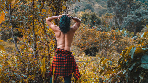 Rear view of woman standing against trees