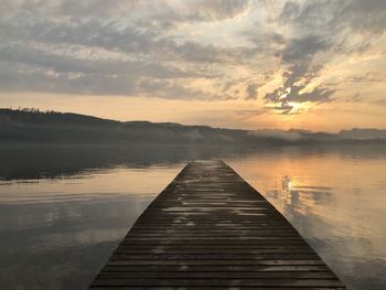 Pier over lake against sky during sunset