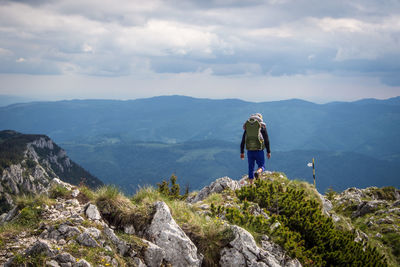 Rear view of man standing on mountain against sky