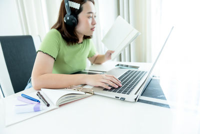 Young woman using mobile phone while sitting on table