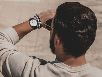 Rear view of man holding camera against blurred background