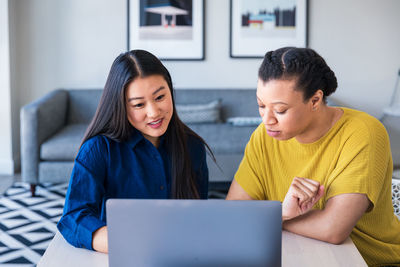 Confident businesswomen discussing over laptop at table in office