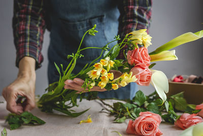 Unrecognizable female professional florist making bouquets of various types. roses. yellow flowers. coves