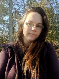 Portrait of beautiful young woman against trees