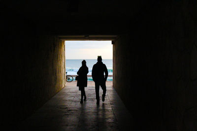Silhouette man and woman walking in tunnel