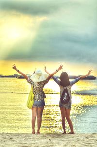 Full length rear view of friends standing on beach