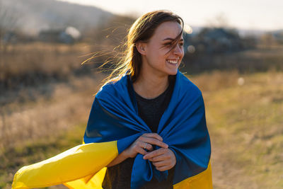 Woman holding a yellow and blue flag of ukraine in outdoors