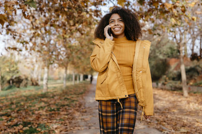 Smiling young woman standing in park during autumn