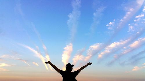 Silhouette of man with arms outstretched in background