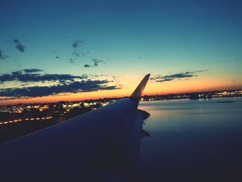 Close-up of airplane wing against sky during sunset