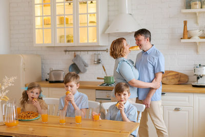 Happy family with three children has breakfast in kitchen in morning sitting