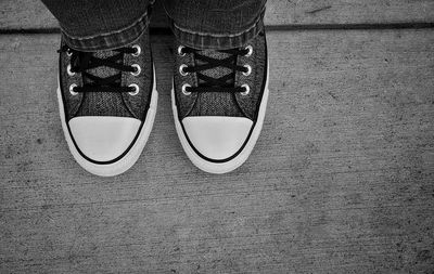 Low section of person in canvas shoe standing on wooden floor