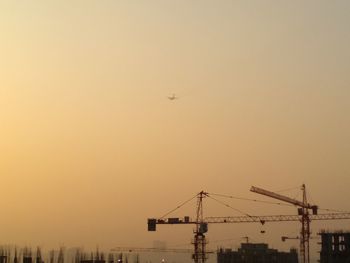 Low angle view of cranes against clear sky during sunset