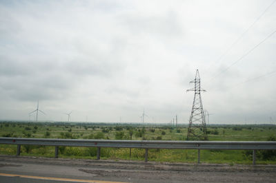 Electricity pylons on field against sky