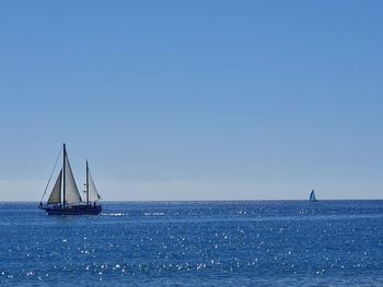 Sailboat sailing on sea against clear sky